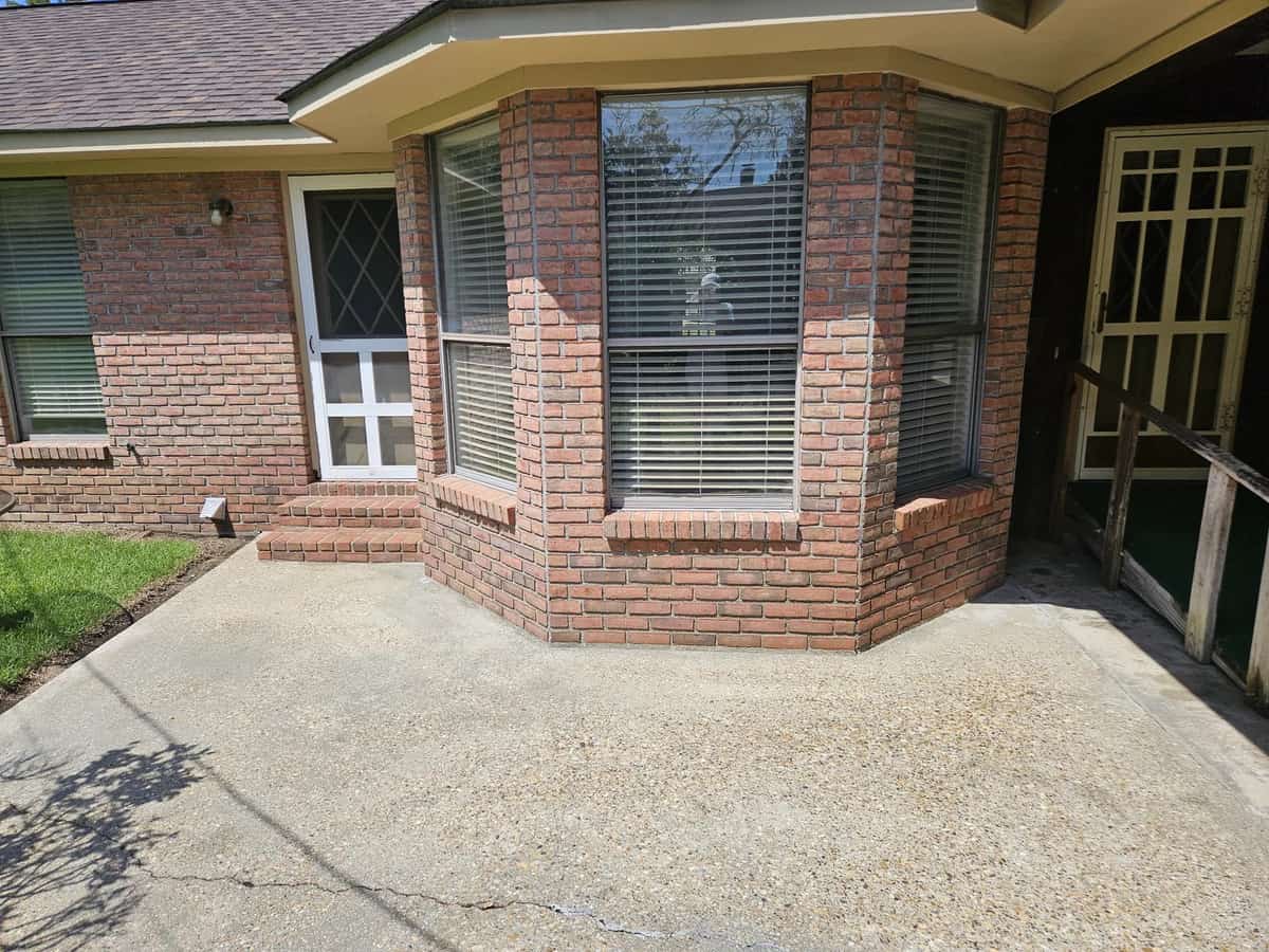 Cleaned concrete beside a brick side entrance at a Collins, Mississippi home