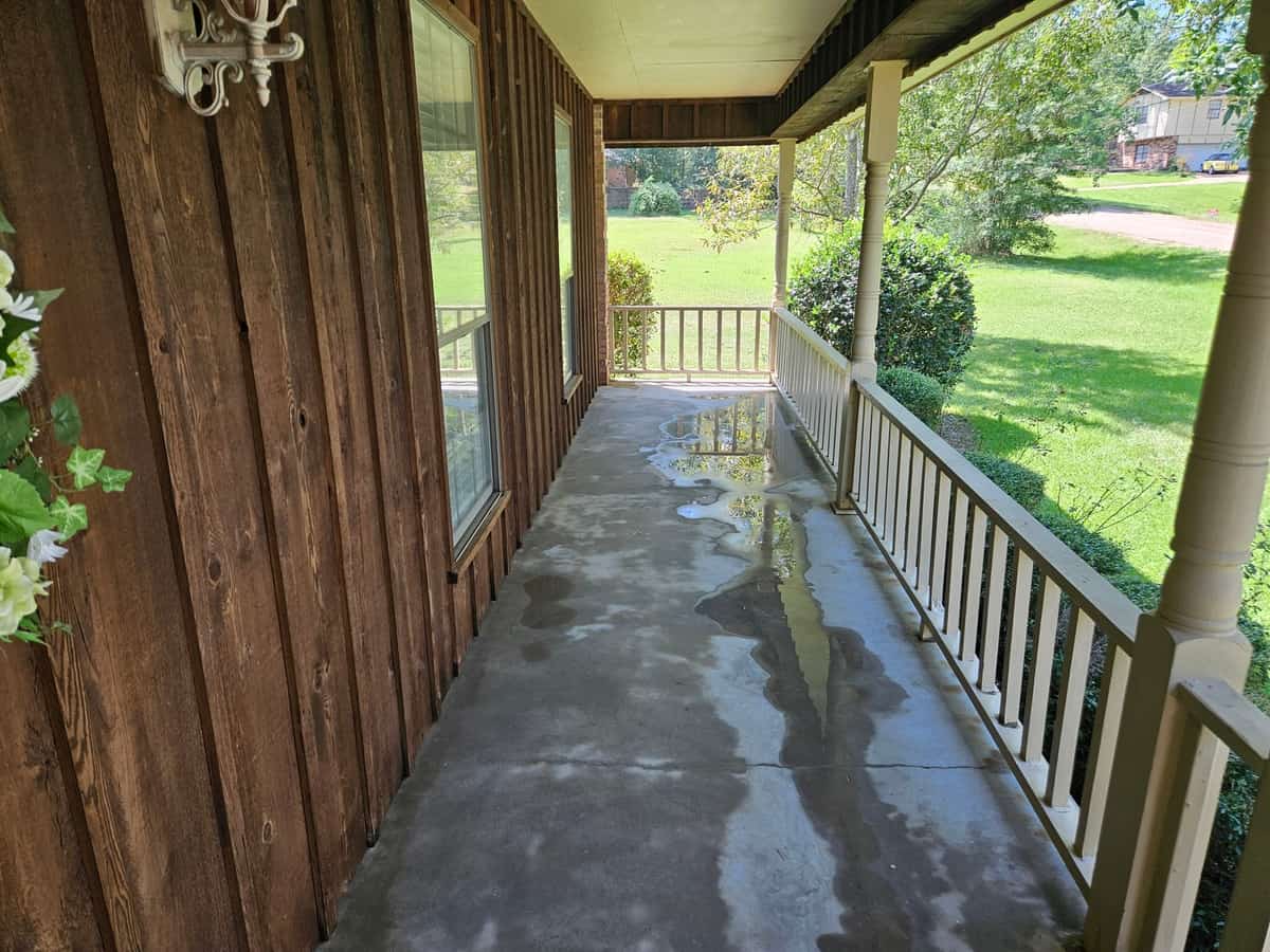 Cleaned concrete porch beside wood siding and white rails in Collins