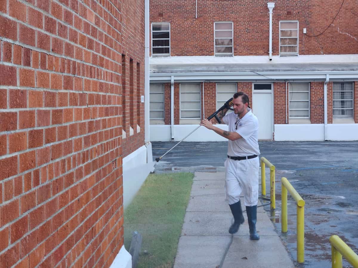 Team member cleaning beside a brick commercial building