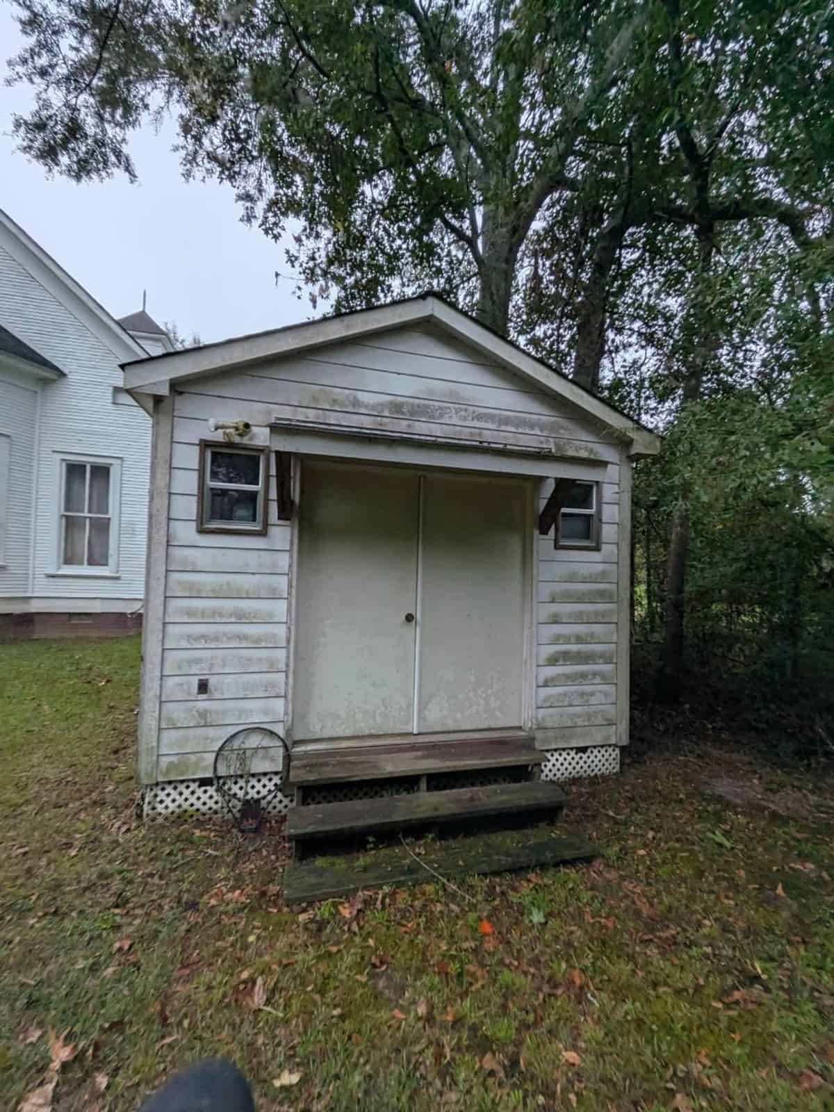 Outbuilding double-door entrance and painted wood siding before cleaning at Harvest Church