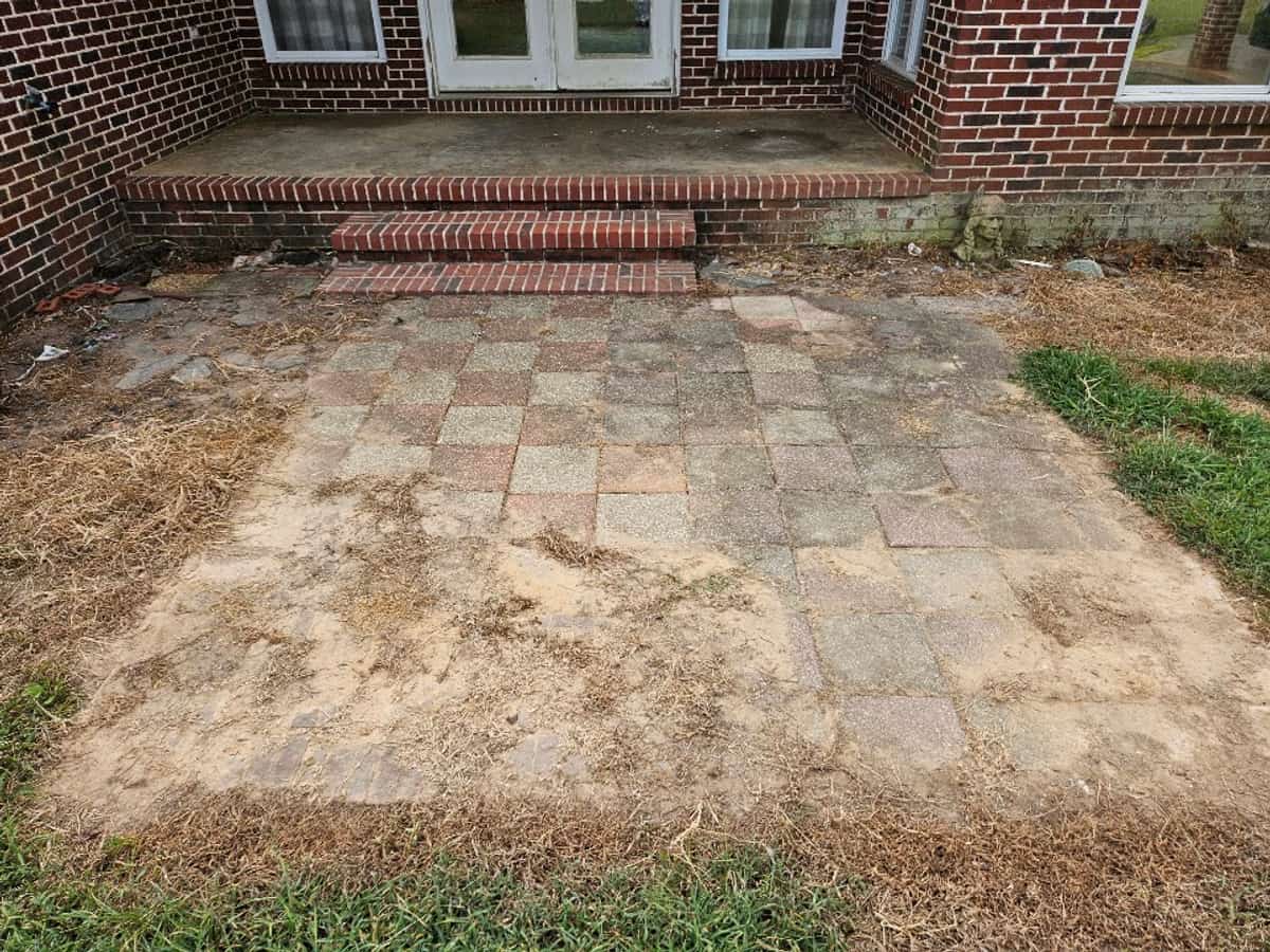 Dark outdoor buildup on red and gray patio pavers before cleaning