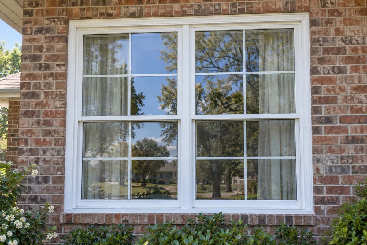 Clean exterior window glass with white trim on a brick home